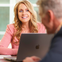 Photo of female employee in front of laptop talking to male employee