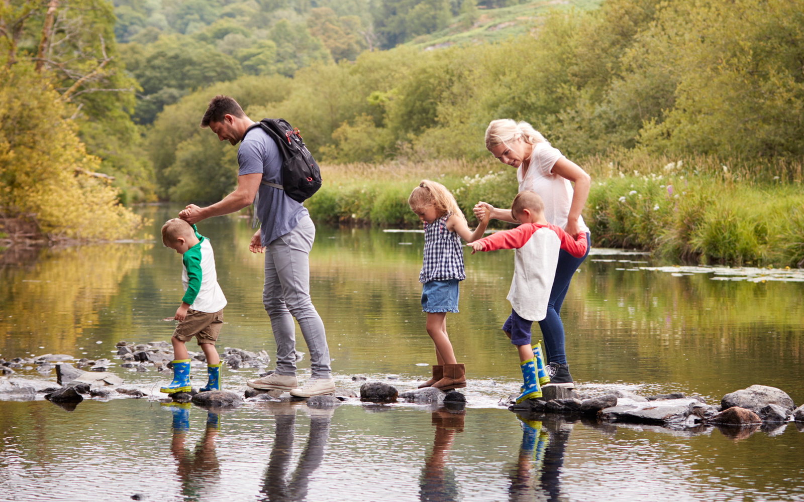 Family walking across creek with three young children
