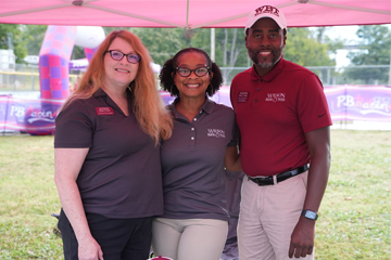 Group photo of 3 WBT employees at event smiling at camera. Two females on left, male on right