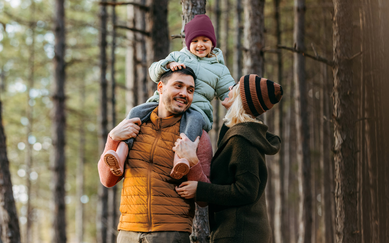 Family with mother, father, and female child, walking through the forest in winter clothing